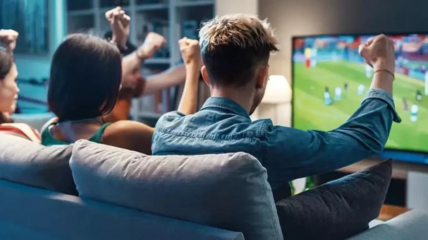 Personas viendo un partido de fútbol en televisión