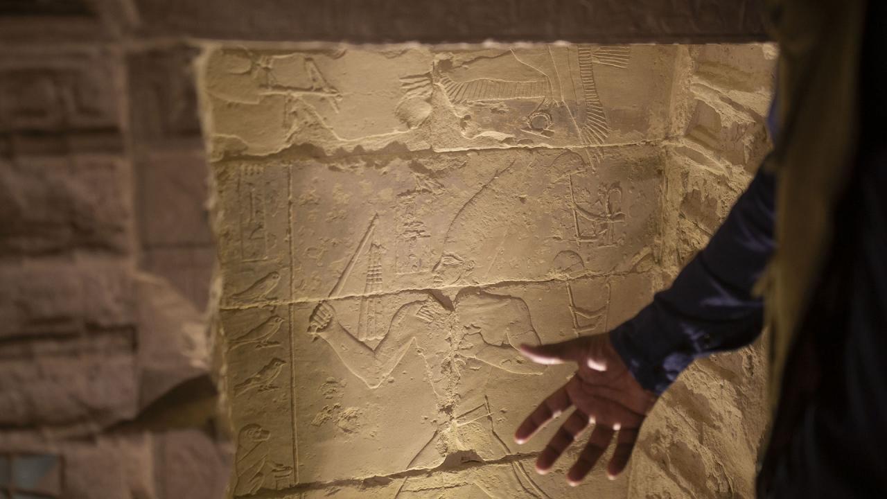 El arqueólogo Ragab Dawood describe una talla de piedra mientras realiza un recorrido 